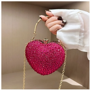 Macro shot of heart-shaped luxury evening bag with pink rhinestones and gold metal handle