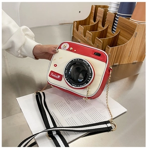 Detail of creative camera-shaped crossbody bag featuring red and cream PU leather texture