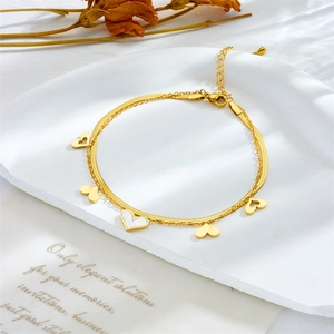 Detail of gold double-layer stainless steel anklet with heart charms and lobster clasp