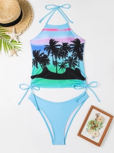 Flat lay of a tropical palm print halter bikini set with sunset gradient and light blue bottoms