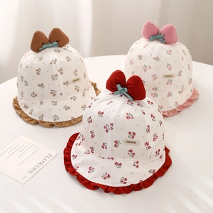 Tre cappellini a fiori per neonati con fiocchi e bordi a onde su tavolo bianco