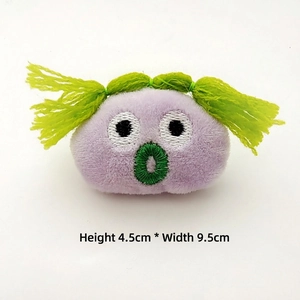 Detail shot of purple plush brooch with green hair, measuring 4.5cm high and 9.5cm wide