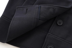 Détail d'un manteau en laine bleu marine avec bouton assorti et texture feutre
