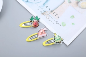 Detailed view of yellow Christmas hair clips with reindeer, hat, and tree acrylic charms