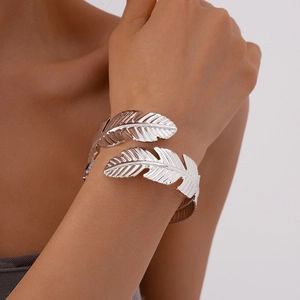 Detailed close-up of a silver-toned double feather open bangle with realistic textures