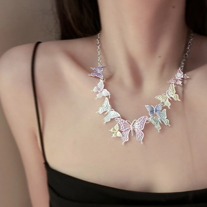 Close-up of a multi-color butterfly pendant necklace worn on a woman's collarbone