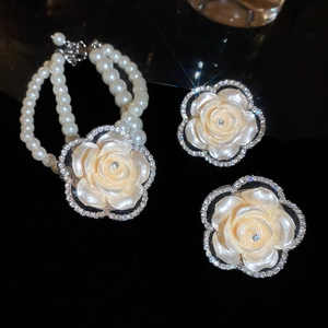 Close-up of double-layer pearl necklace and earrings with crystal-encrusted camellia