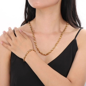 Modell trägt ein Set aus goldener Halskette und Armband mit gedrehten Gliedern