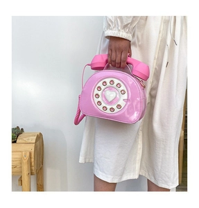 Detail of pink retro telephone shaped handbag with rotary dial and handset handle