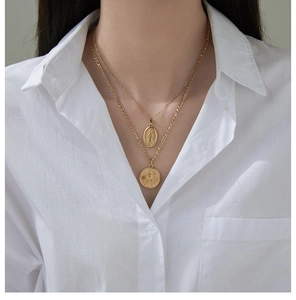 Close-up of layered 18K gold plated necklaces featuring Virgin Mary and angel pendants