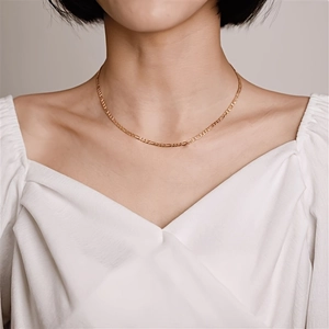 Detail of 18K gold Figaro chain necklace on model with polished metallic texture