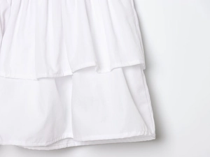 Close-up detail of white halter mini dress showing layered ruffle trim and fabric texture