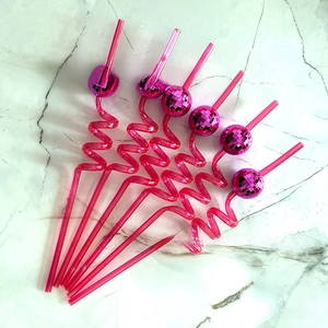 Macro view of six pink wavy party straws decorated with shiny mirror disco balls on top