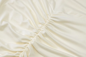 Detailed view of beige pleated mesh fabric and fine stitching on a stretch dress