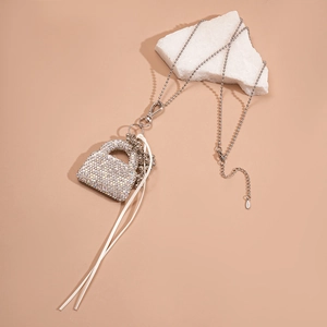 Sautoir argenté avec pendentif sac à main en strass et pompon blanc sur socle en pierre