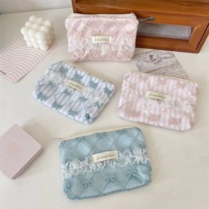 Detailed view of lace floral makeup pouches in pink and blue with bow embroidery