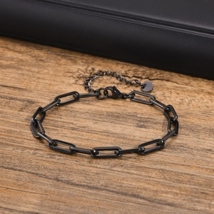 Macro shot of matte black paperclip chain bracelet with lobster clasp on wood texture