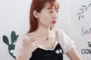 Close-up of golden leaf necklace and earrings set worn by a model in soft lighting