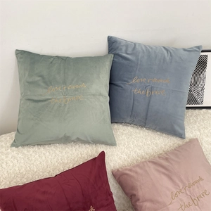 Detail of embroidered gold lettering on velvet cushion covers in Morandi colors
