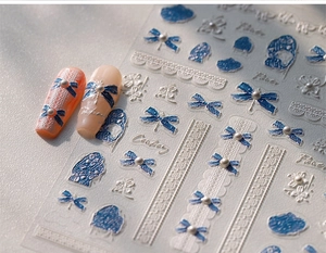 Detail of 5D embossed nail stickers featuring blue bows and 3D pearls on matte tips