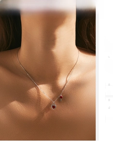 Detail of s925 silver necklace featuring red heart lock and key charms on model