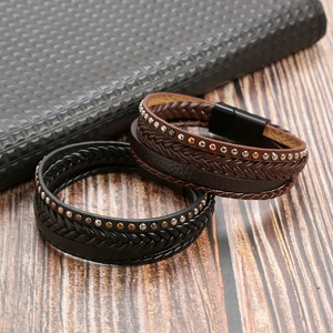 Detail of layered brown and black woven leather bracelets with metal studs and magnetic clasp