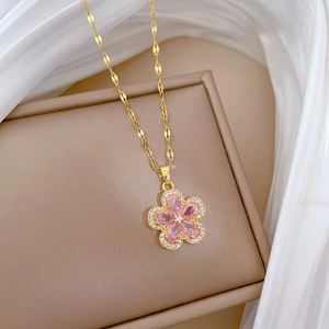 Close-up of golden necklace with pink flower pendant on beige jewelry box and silk