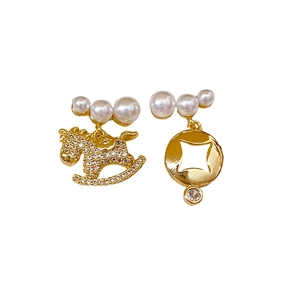 Boucles d'oreilles cheval asymétriques en or avec perles et cristaux sur fond blanc