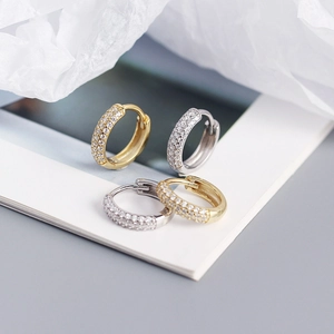 Detail of silver and gold huggie earrings with double-row micro-pave cubic zirconia