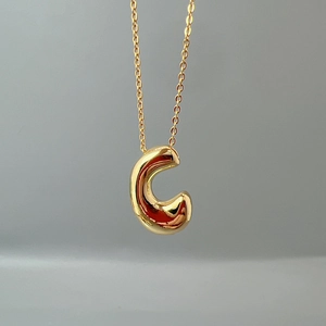 Detailed close-up of golden alphabet C pendant necklace on a sleek O-chain link