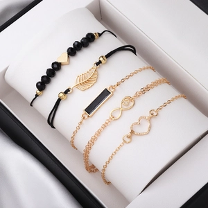Détail d'un ensemble de 5 bracelets or et noir avec breloques cœur sur coussin bijoux