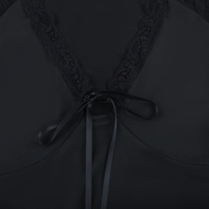 Close-up of black floral lace trim and delicate ribbon bowtie on the V-neckline