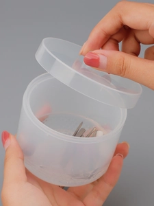 Macro shot of translucent round nail art storage box holding metal drill bits