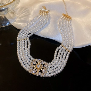 Detail of multi-layer pearl necklace with square rhinestone buckle on white silk fabric