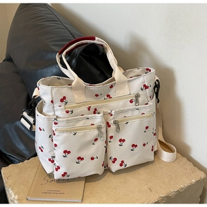 Detailed macro view of cherry print canvas tote bag with metal zippers and pockets