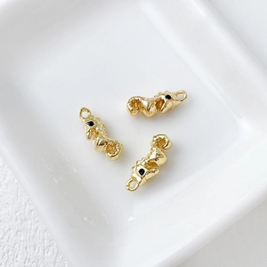 Macro shot of three 14k gold-plated seahorse pendants with black stone eyes for DIY jewelry