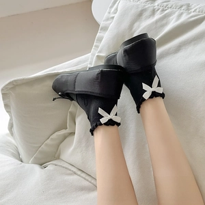 Detail of black cotton JK socks with white ruffle trim and 3D bow accent