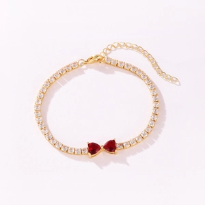 Close-up of elegant gold tennis bracelet with red heart-shaped crystals