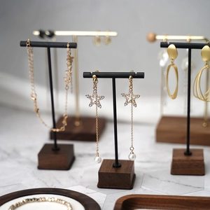 Detail of gold star earrings with pearls on a wood and metal jewelry display stand