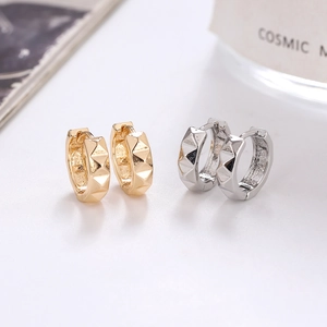 Macro shot of gold and silver pyramid studded geometric hoop earrings on a white background