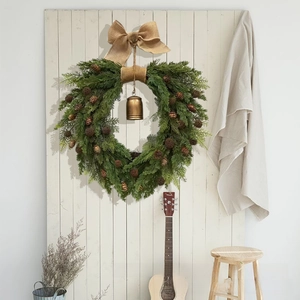 Detailed view of a natural Christmas wreath with burlap bow and vintage gold bell