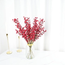 Detail of decorative red artificial berries in a glass vase for home interior styling