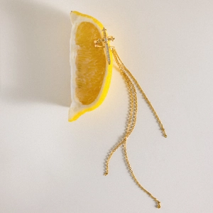 Close-up of golden sword-shaped ear cuff with sparkling zircons and delicate tassels