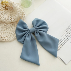 Detail of Morandi blue bow hair clip with textured satin fabric on vintage lace background