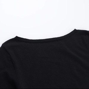 Detalle del escote del vestido de punto negro con acabado de dobladillo ondulado