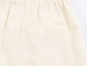 Dettaglio della vita elastica e della cucitura della tasca su pantaloni a gamba larga panna