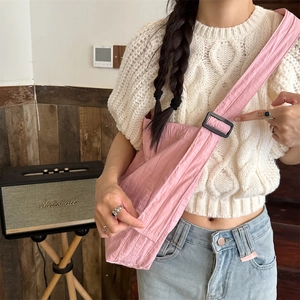 Detail of pink canvas pleated shoulder bag with adjustable buckle strap and soft texture