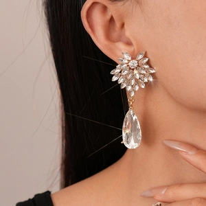 Macro detail of teardrop crystal earrings with floral marquise studs and gold plating