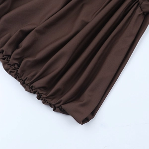 Détails rapprochés du tissu froncé marron et des poignets élastiques d'une robe tricot