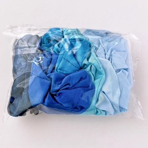 Detail shot of assorted blue satin scrunchies in transparent packaging on white background